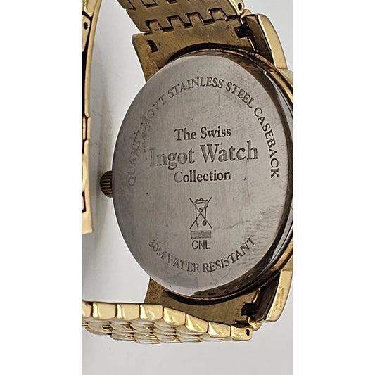 Close-up of the back of a wristwatch showing a brushed stainless steel caseback engraved with 'The Swiss Ingot Watch Collection' and 'Quartz-Move Stainless Steel Caseback', with a gold-tone metal bracelet visible around it.