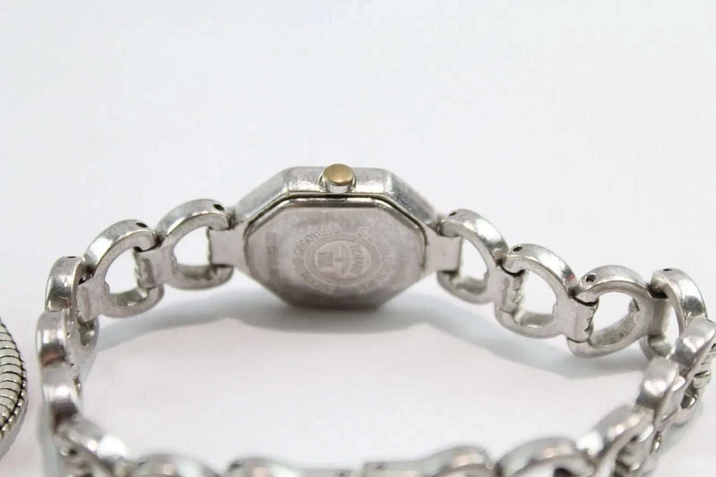 Silver-tone metal watch bracelet with a central octagonal case end and interlocking links, photographed on a plain light background.