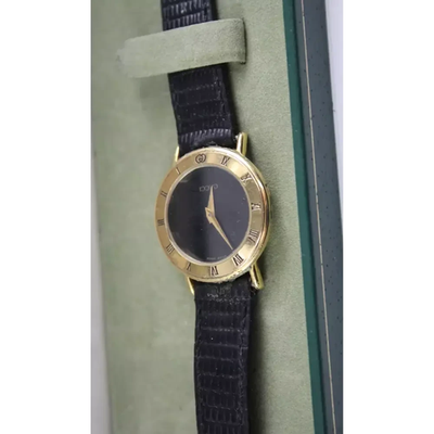 Gold watch with black strap on a green cushion from our Pre-Owned & Secondhand Watches
