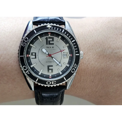 Wrist wearing a black wristwatch with a silver case on a ligh backgroundt from our Pre-Owned & Secondhand Watches
