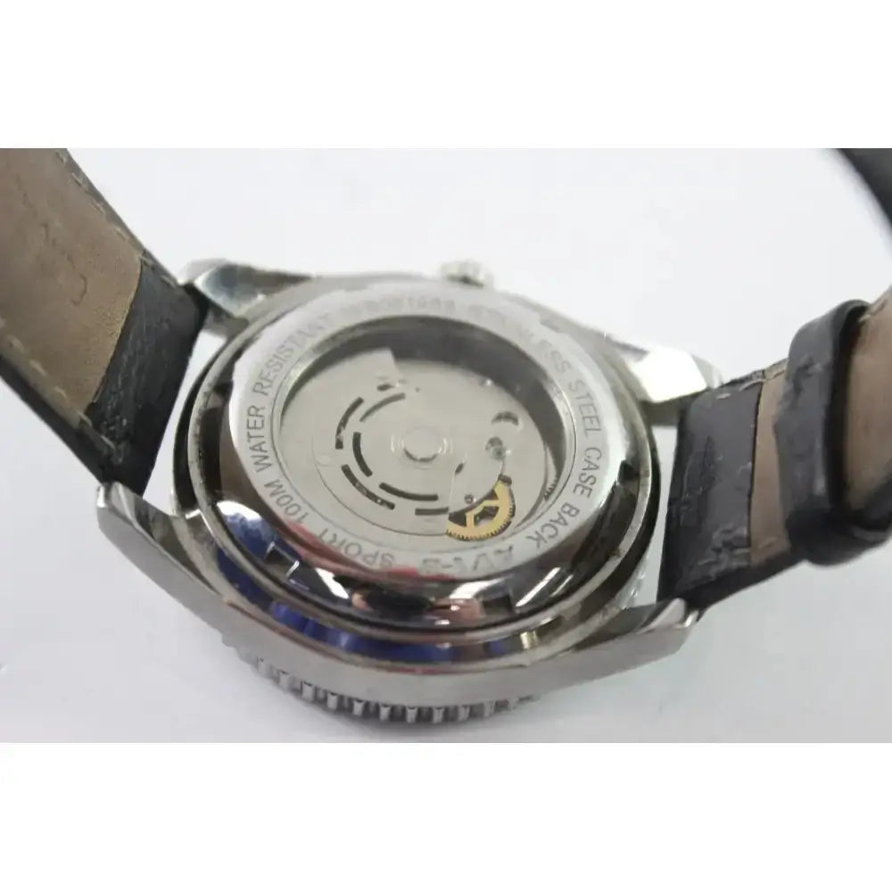 Close-up of the back of a wristwatch showing a polished stainless steel case back with a transparent window and a dark leather strap on a white background.