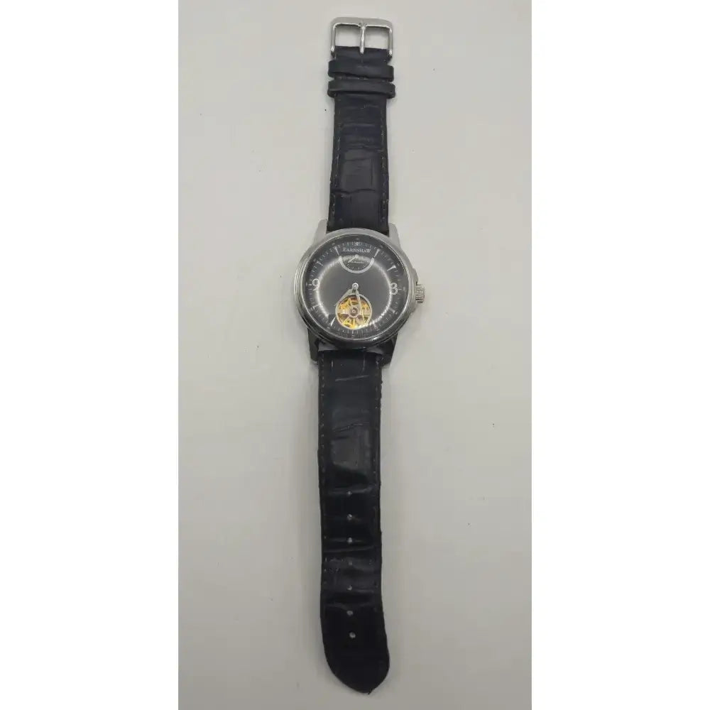 A wristwatch with a black textured strap, silver-toned case, and a skeleton dial showing a gold-toned mechanical movement, photographed against a plain light background.