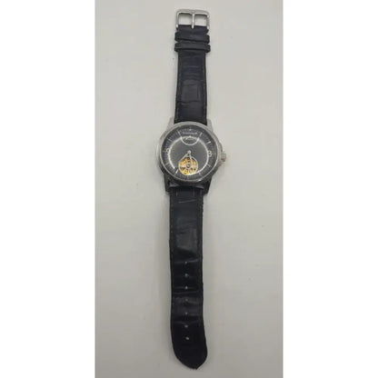A wristwatch with a black textured strap, silver-toned case, and a skeleton dial showing a gold-toned mechanical movement, photographed against a plain light background.