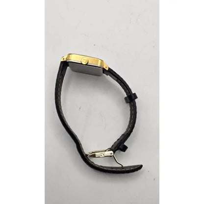 A smartwatch with a rectangular gold-tone case and a black textured strap, shown from a side angle on a light gray background.