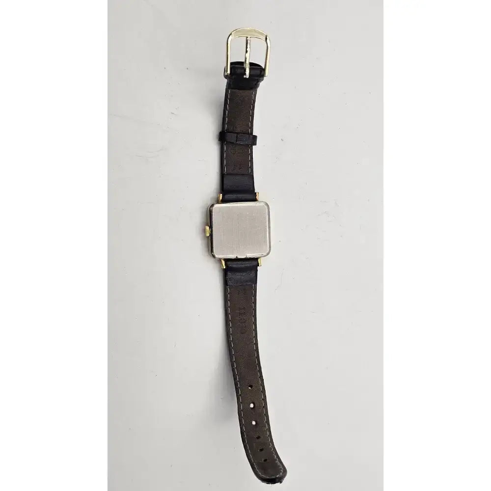 A vintage-style wristwatch with a dark brown leather strap, a square silver-toned metal case, and gold-tone hardware, shown against a plain light gray background.