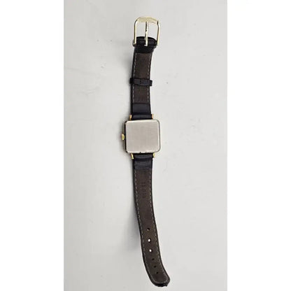 A vintage-style wristwatch with a dark brown leather strap, a square silver-toned metal case, and gold-tone hardware, shown against a plain light gray background.