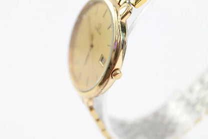 A close-up shot of a gold-tone wristwatch with a champagne dial and a silver-tone metal bracelet, shown against a plain white background.
