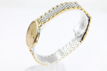 A two-tone wristwatch with a gold-toned oval case, cream dial, and a mesh bracelet combining gold and silver-toned metal links, shown on a white background.