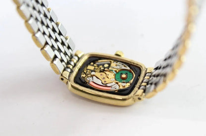 A close-up of a two-tone metal watch with a gold-toned case and a silver-and-gold link bracelet, featuring a visible multicolor mechanical movement inside the rectangular watch face.