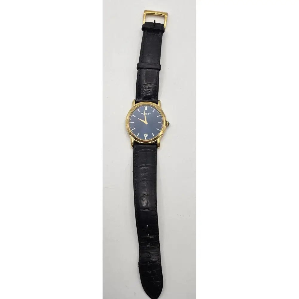 A vintage wristwatch with a round gold-tone case, a blue dial, and a black leather strap, shown vertically against a light gray background.