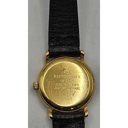 Back view of a vintage Raymond Weil wristwatch with a gold-toned case and a black leather strap, showing engraved details on the case.