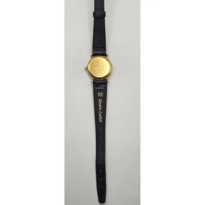 A vintage wrist watch with a round gold-tone case and a black leather strap, shown from the back against a light gray background.