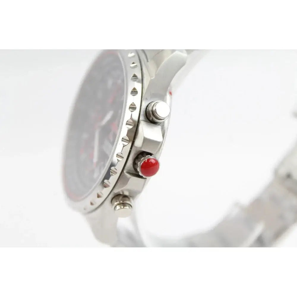 Close-up side view of a stainless steel wristwatch with a silver bezel, dark dial, and a prominent red button accent on a white background.