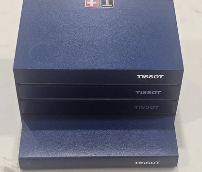 Three stacked Tissot watch boxes in a dark blue textured finish, with the Tissot logo printed on the front and top.