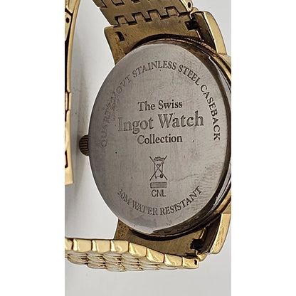 Close-up of the back of a wristwatch showing a brushed stainless steel caseback engraved with 'The Swiss Ingot Watch Collection' and 'Quartz-Move Stainless Steel Caseback', with a gold-tone metal bracelet visible around it.