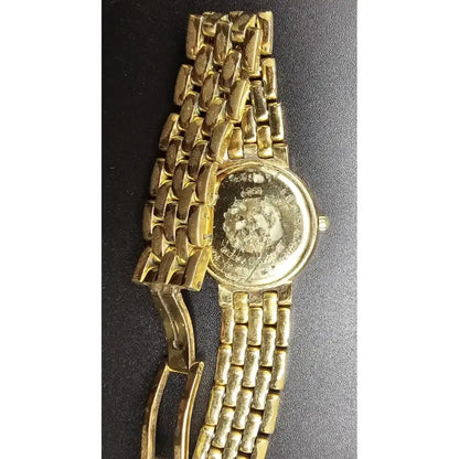 A vintage gold-tone metal link watch with a round case, shown on a dark textured background.