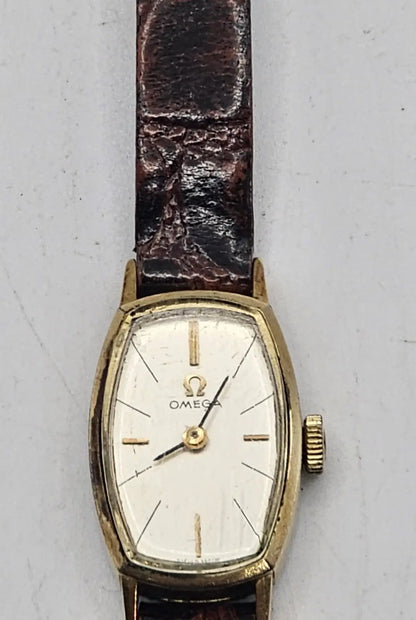 Omega wristwatch with a gold-tone case, white dial, and dark brown leather strap, photographed against a light gray background.
