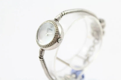 A silver-toned watch with a textured bangle strap and a round dial accented with small clear stones, shown on a white background.
